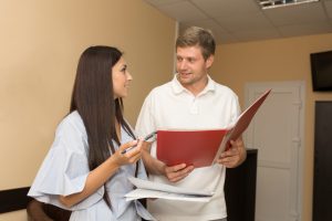 A health professional holding a file talking to a patient.