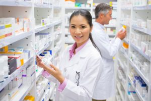 Two pharmacists standing near pharmacy shelves.