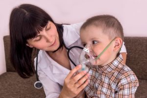 Respiratory therapist places an oxygen mask on a child.