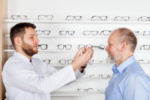 An optician helps a customer try on a pair of eyeglasses.