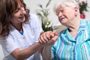A health professional holds the hand of an older patient.